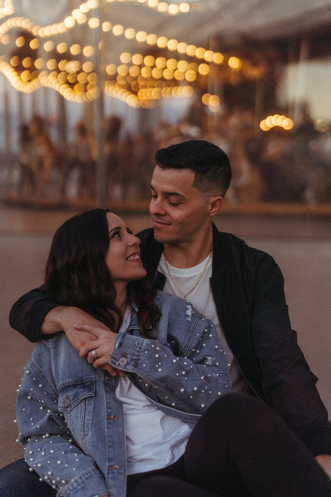 Couple looking at each other with a carousel in the background.
