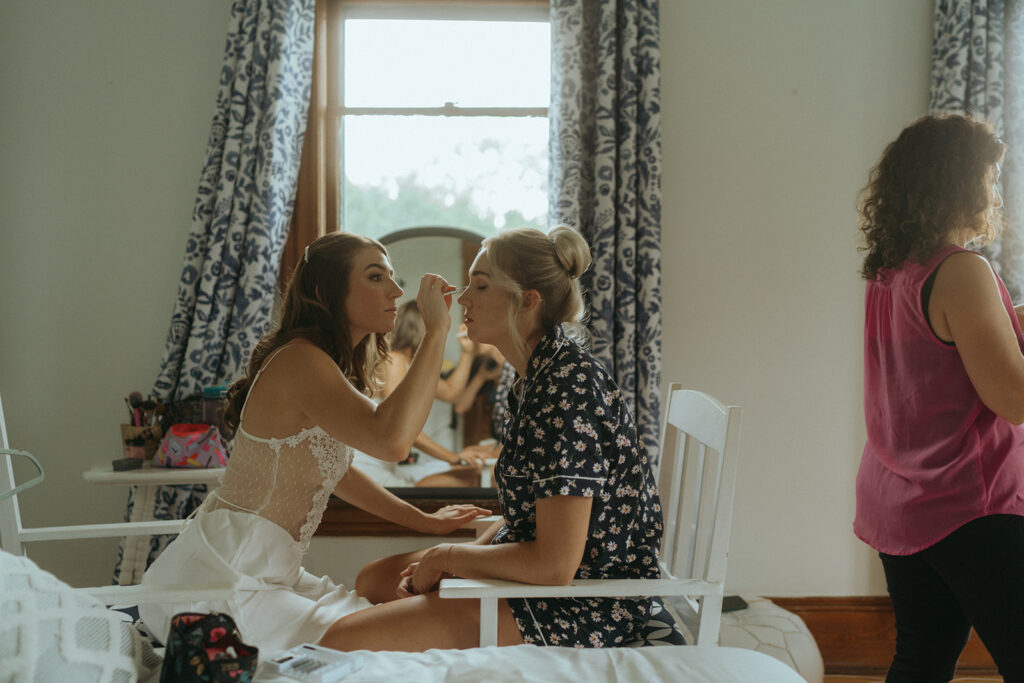Bride getting makeup done on wedding day.
