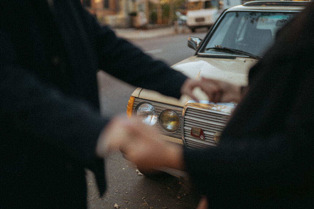 Close up of a couple's hands and a car in the street.