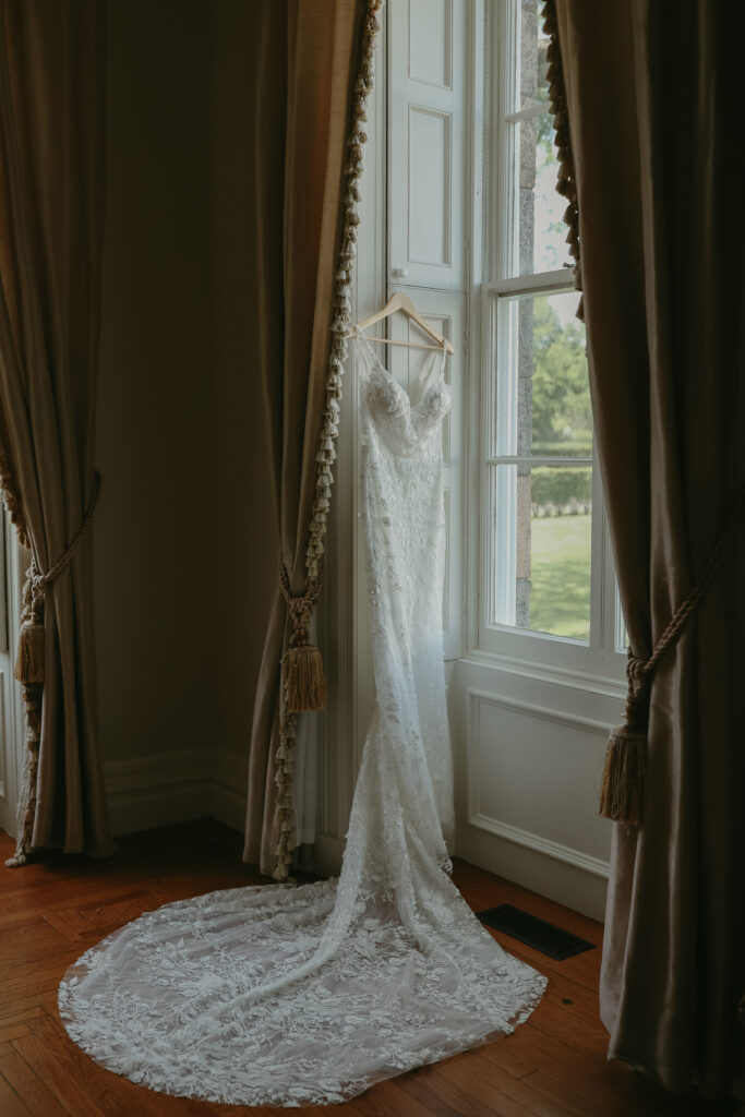 Bride's dress hanging by a window in the bridal suite.