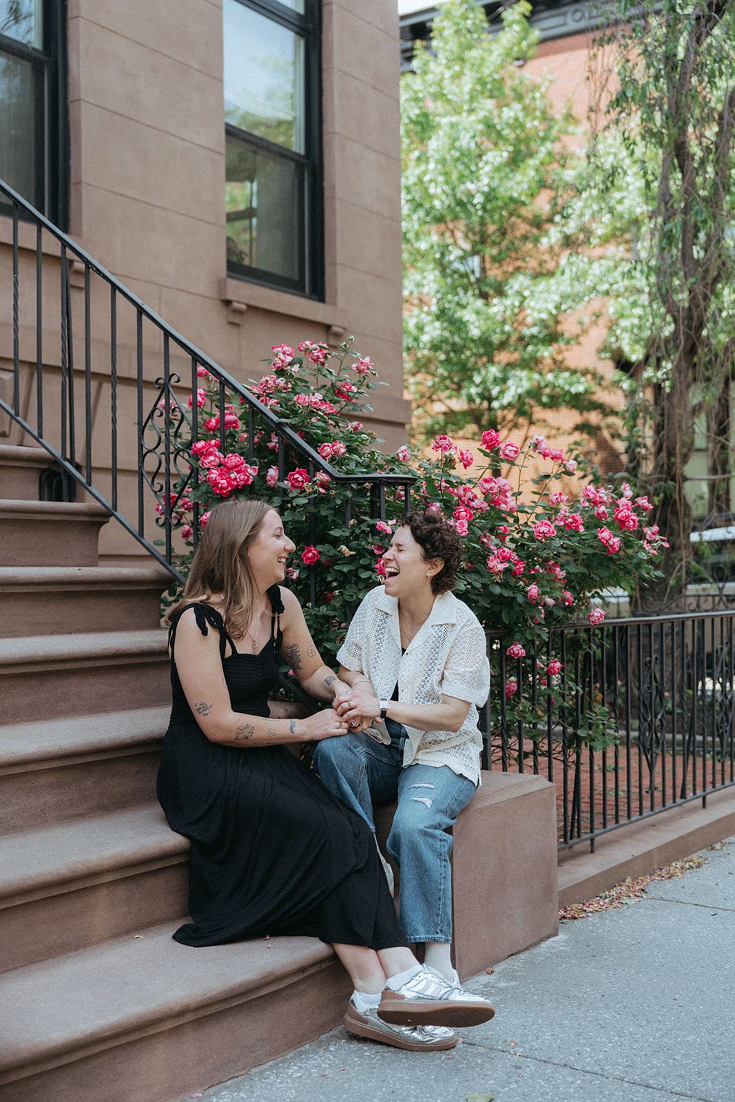 Couple sitting on a rose-covered brownstone stoop in Brooklyn Heights for their engagement session.