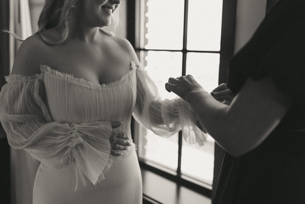 Bride and bridesmaid getting dressed