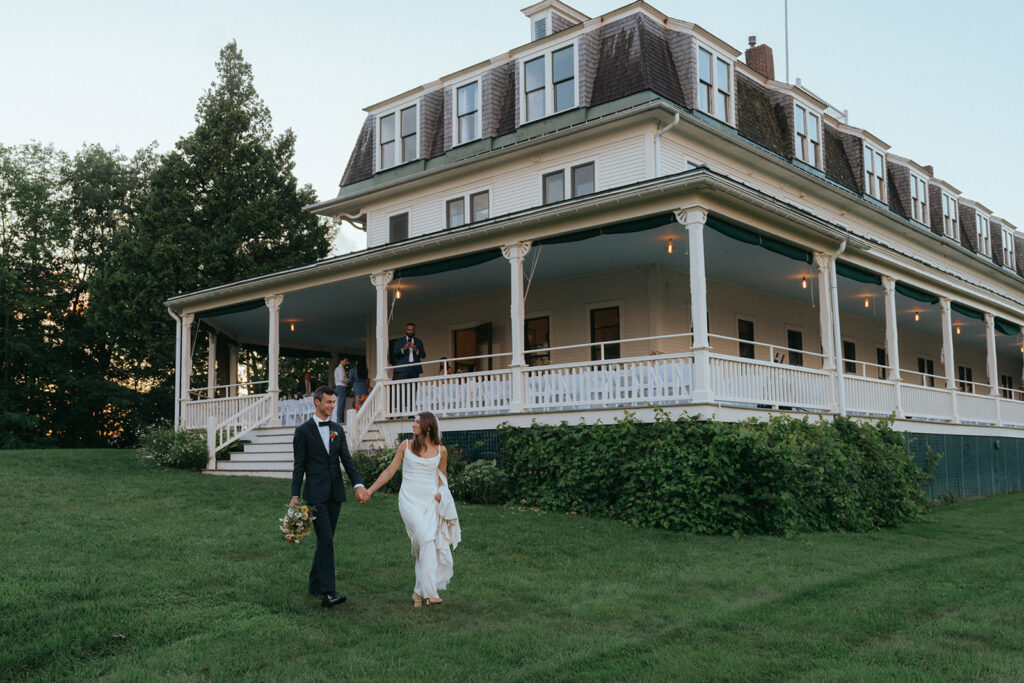 Bride and groom holding hands in front of Grand Isle Lake House.