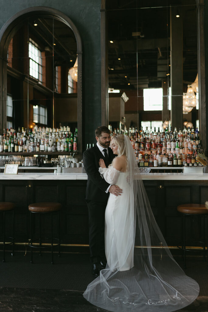 Bride and groom kissing at bar on wedding day