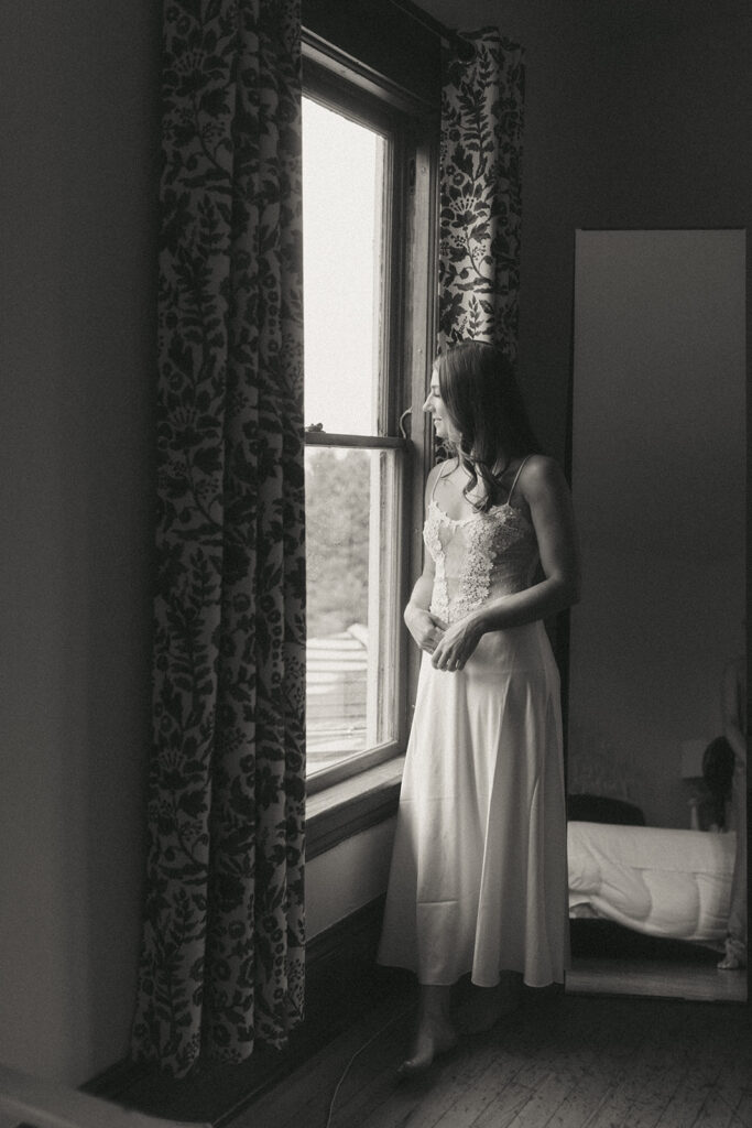 Bride getting ready on her wedding day looking out the window.
