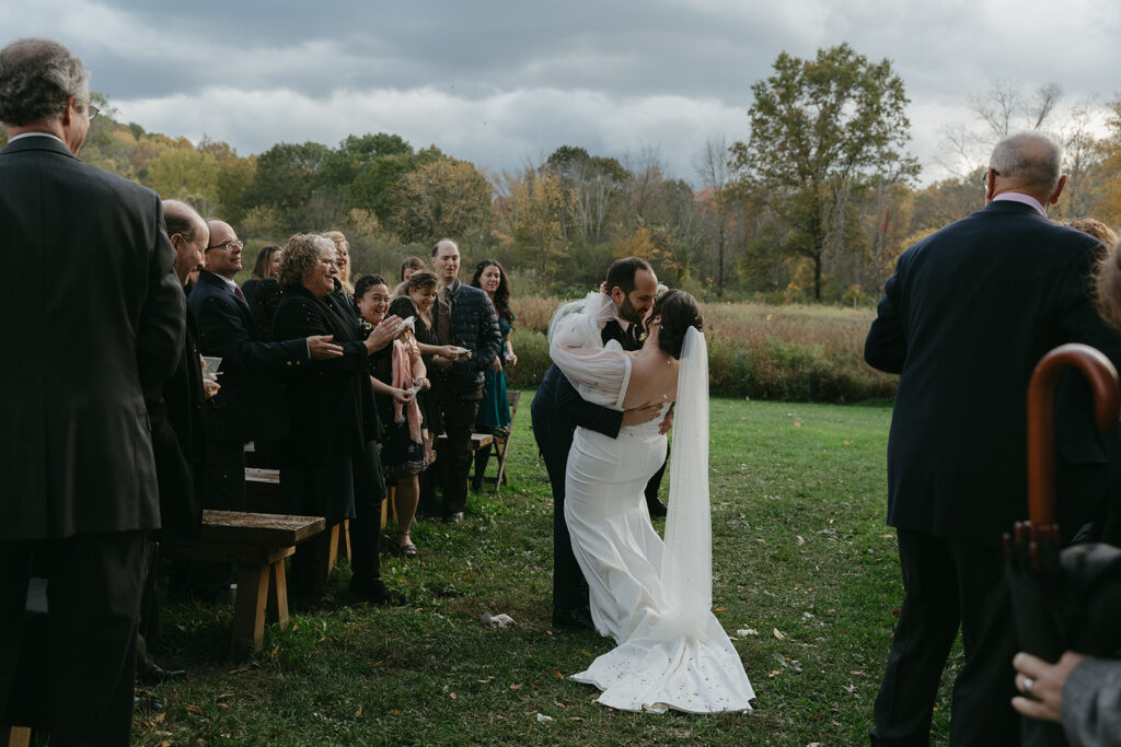 Bride and groom walking up the aisle at their ceremony, flower petals being thrown at them