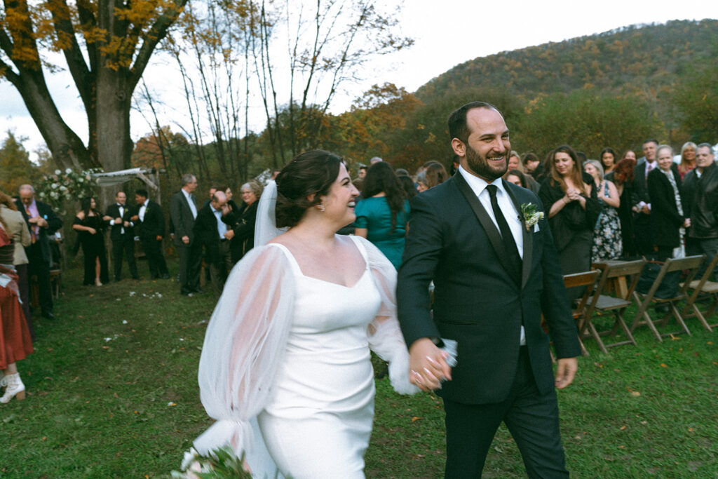 Bride and groom walking up the aisle at their ceremony, flower petals being thrown at them