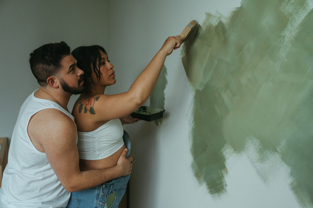 A husband and pregnant wife paint the nursery for their baby-to-be.