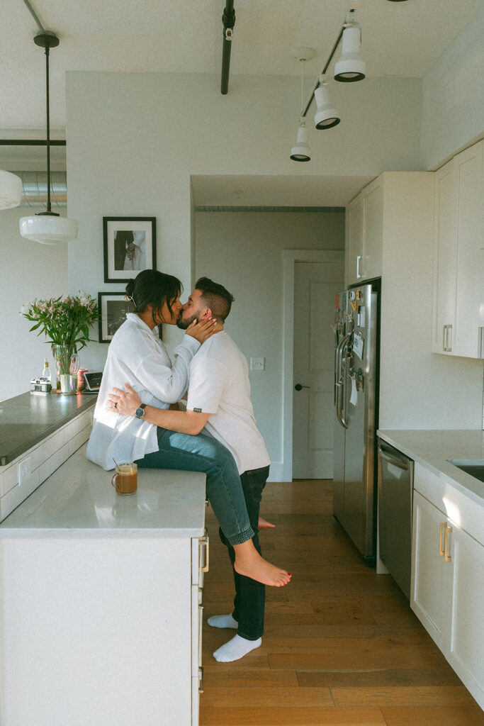 A husband and pregnant wife making coffee in their NYC apartment kitchen during a maternity photography session.