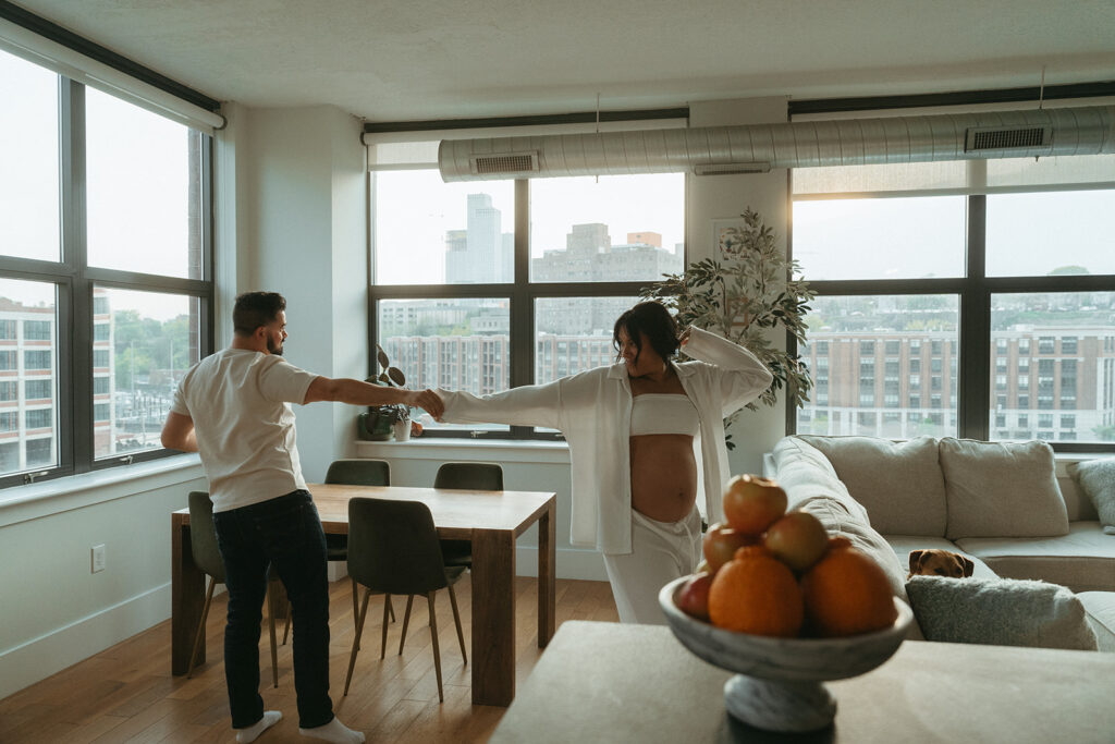 A husband and pregnant wife dancing around their NYC apartment living room.