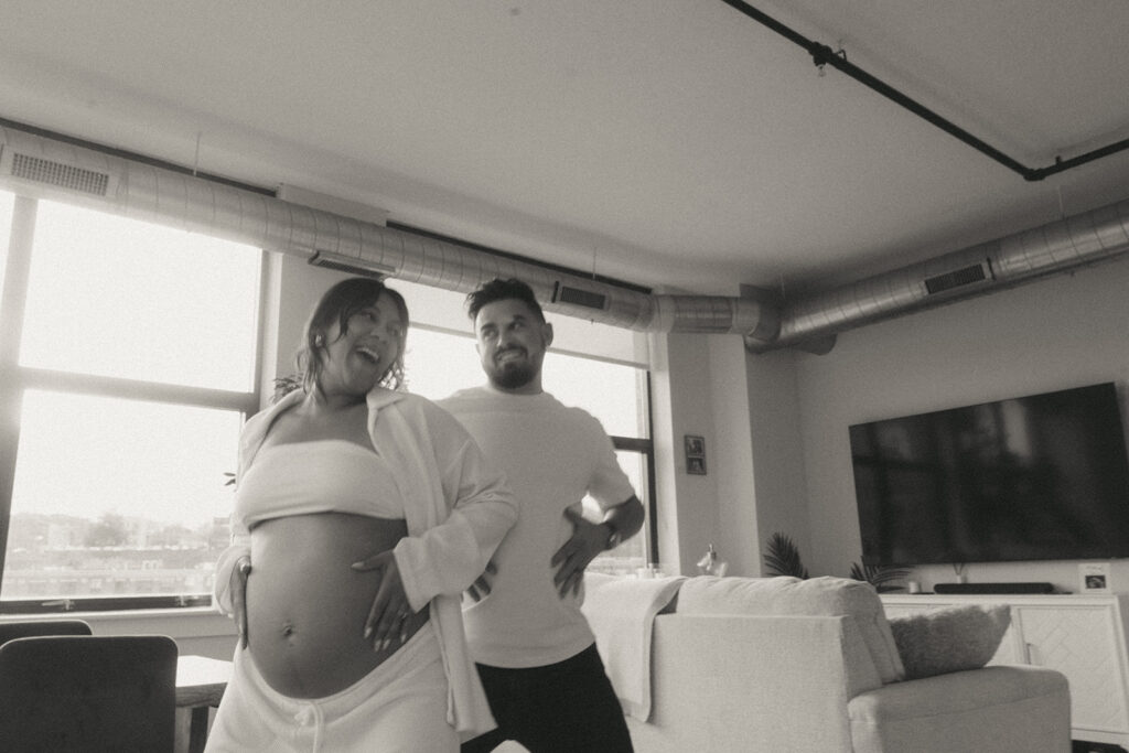 A husband and pregnant wife dancing around their NYC apartment living room.