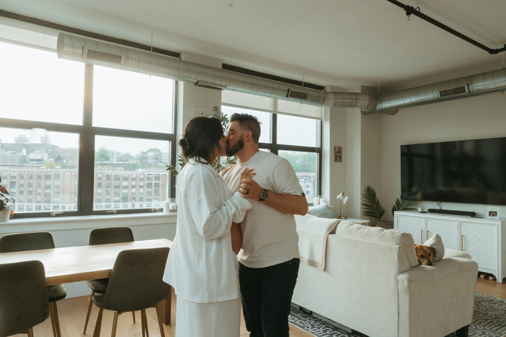 A husband and pregnant wife kissing in their NYC apartment living room during a maternity photography session.