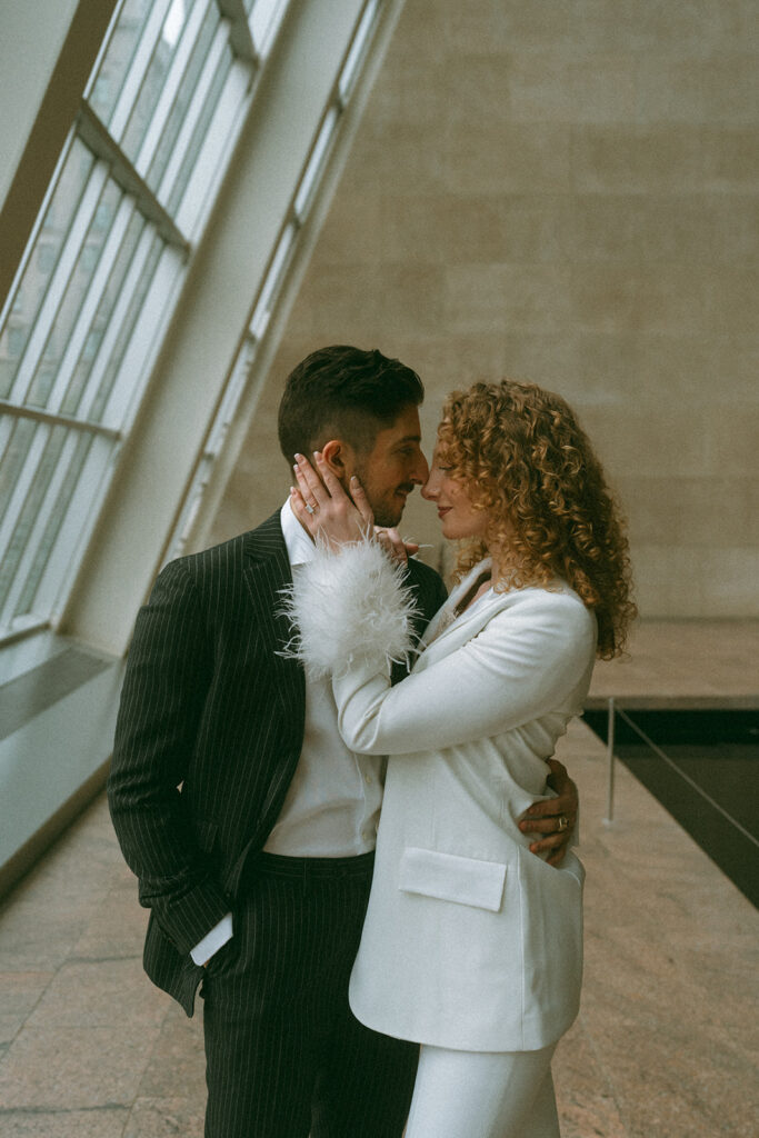 Man in a pinstripe suit and woman in a white suit celebrating their engagement photos at the Met