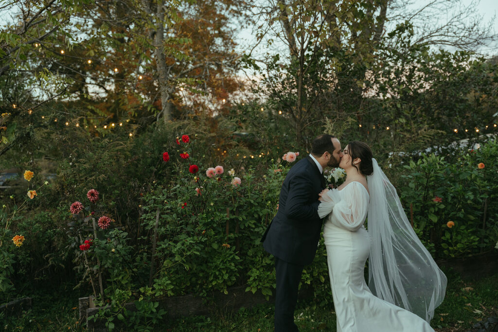 A groom and bride kissing in flower fields during their Blooming Hill Farm wedding.