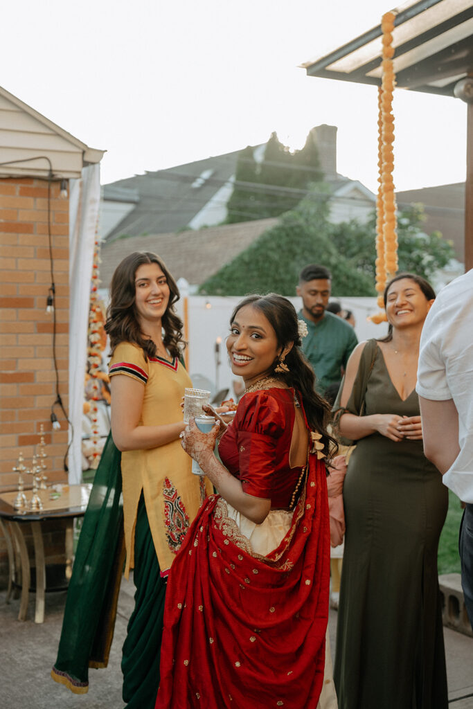 Bride smiling with friends while holding a drink at Catholic Indian wedding welcome party — Elsie Goodman Photography.