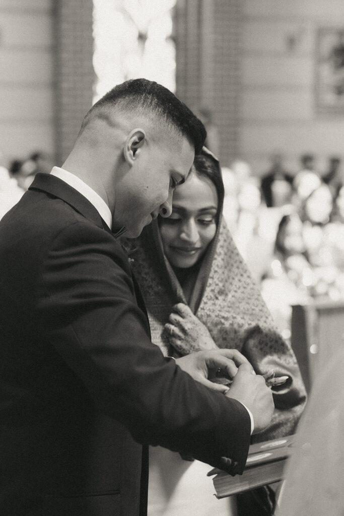The groom gently places the wedding ring on his bride's finger during the Catholic Indian wedding ceremony, a meaningful exchange captured by Elsie Goodman Photography for an Indian wedding photo gallery.