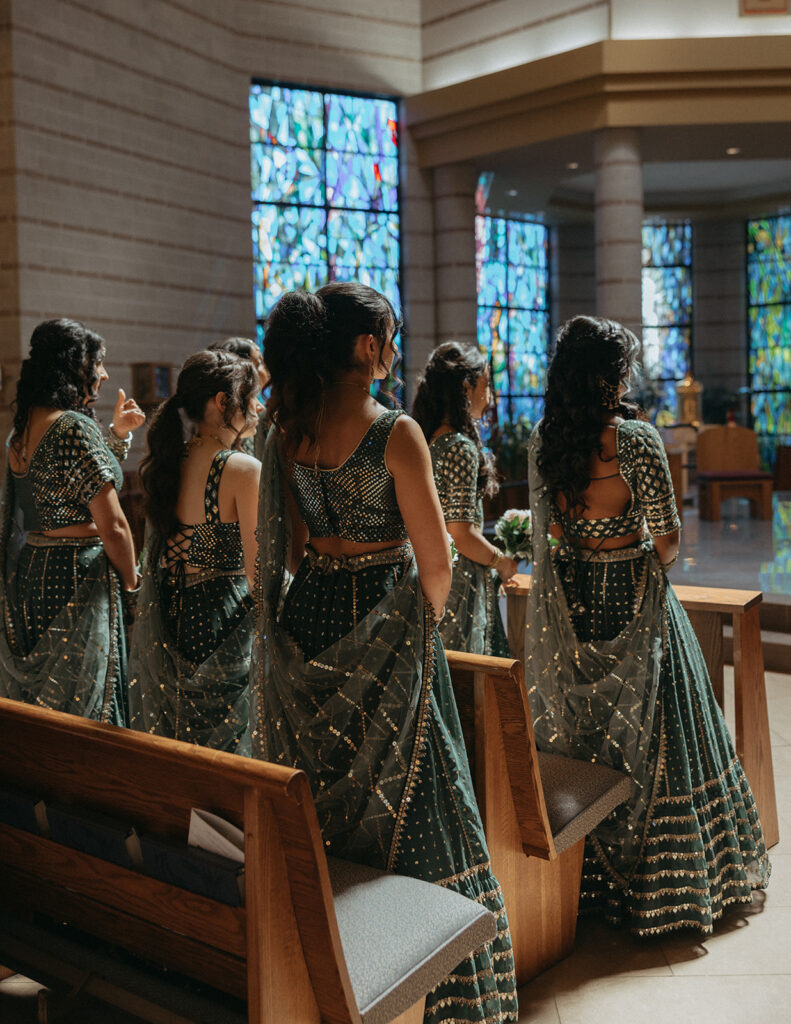 Bridesmaids dressed in sparkling green lehengas look on during the Catholic Indian wedding ceremony, highlighting beautiful Indian catholic wedding dresses captured by Elsie Goodman Photography for an Indian wedding photo gallery.