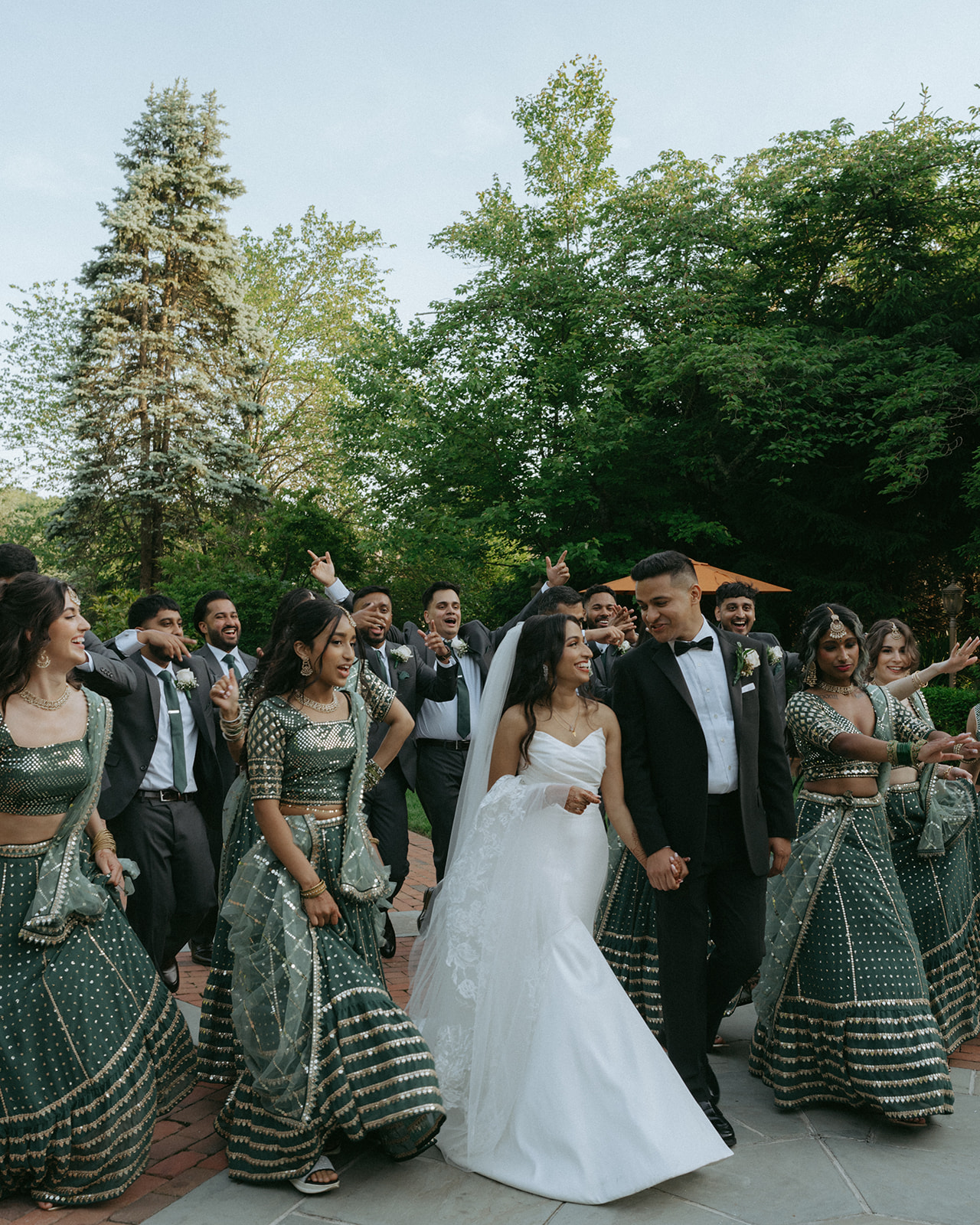 Groom and groomsmen laughing together outside in a fun wedding party moment, captured by Elsie Goodman Photography at an Indian Catholic wedding.