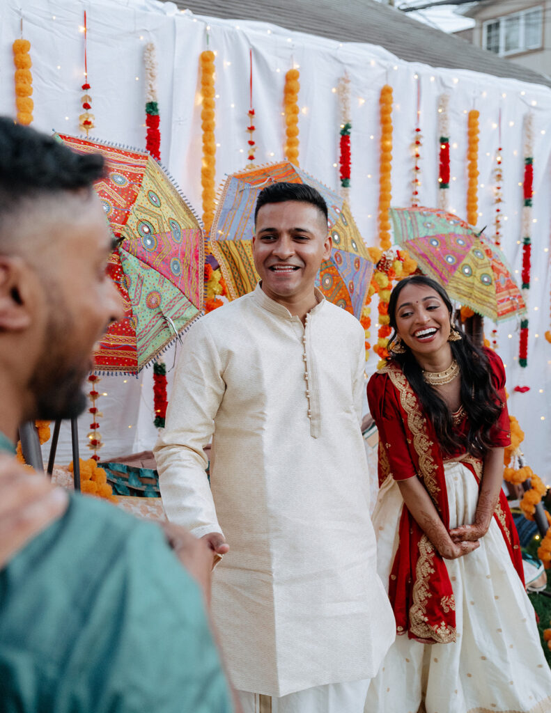 Groom and bride laughing with a guest during Catholic Indian wedding welcome party — Elsie Goodman Photography.