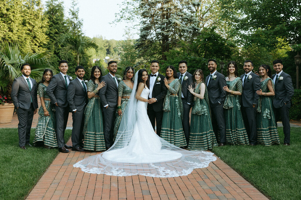 Bride and groom standing at the center of their wedding party for formal group portraits in lush gardens, captured by Elsie Goodman Photography.