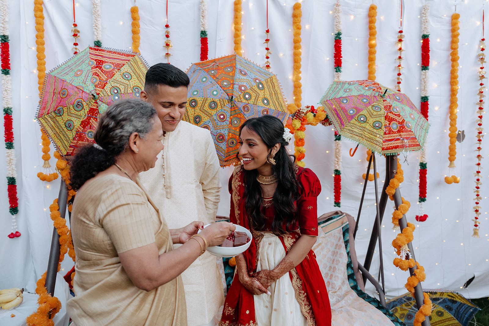 Guest smiling while holding a bowl of chocolates and pomegranate to feed the bride and groom at the night before an Catholic Indian wedding — Elsie Goodman Photography.