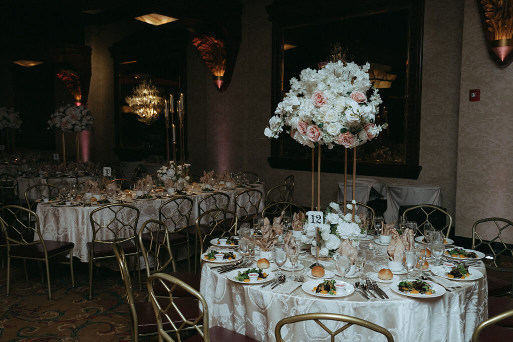 A beautifully set reception table with lush floral centerpieces and elegant place settings at a Catholic Indian wedding reception at Crest Hollow Country Club, showcasing stunning Long Island wedding decor photographed by Elsie Goodman Photography.