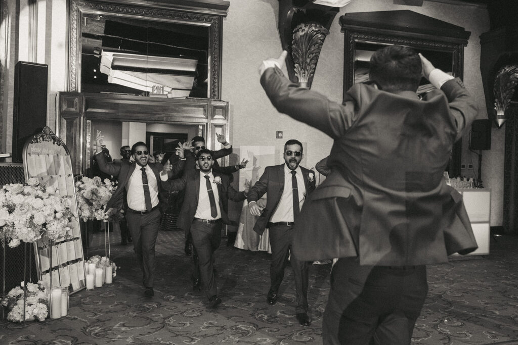 Groomsmen wearing sunglasses make a spirited reception entrance at an Indian catholic wedding at Crest Hollow Country Club, captured candidly by Elsie Goodman Photography for an energetic Indian wedding photo gallery in Long Island.