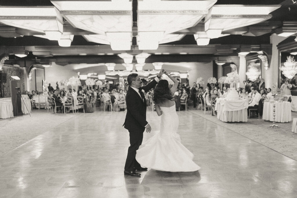 The bride shares an emotional first dance with her father under the grand chandeliers at Crest Hollow Country Club during a beautiful Catholic Indian wedding reception, captured by Elsie Goodman Photography for their Indian wedding photo gallery showcasing Long Island wedding moments.