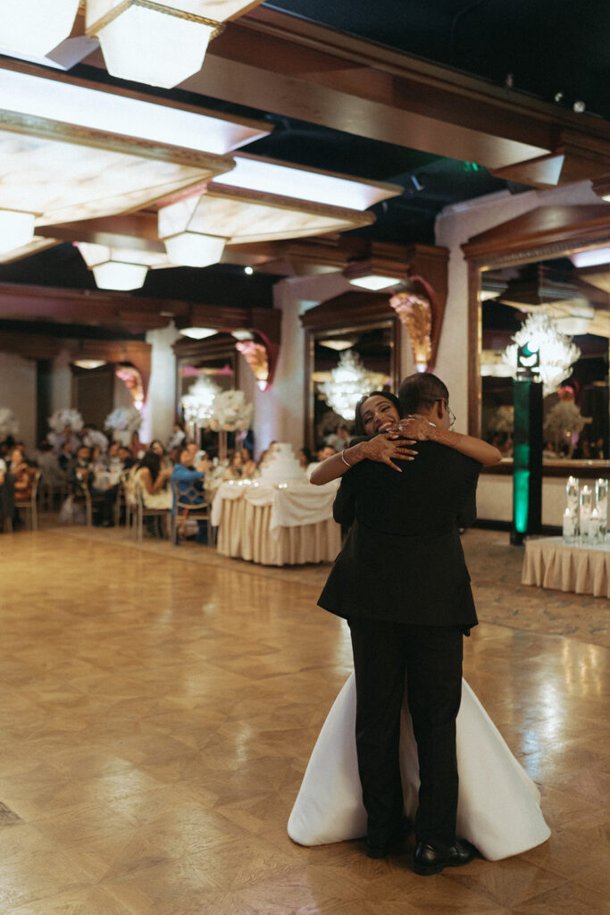 The bride embraces her father during a touching father-daughter dance at their Catholic Indian wedding reception at Crest Hollow Country Club, captured tenderly by Elsie Goodman Photography for an Indian wedding photo gallery.