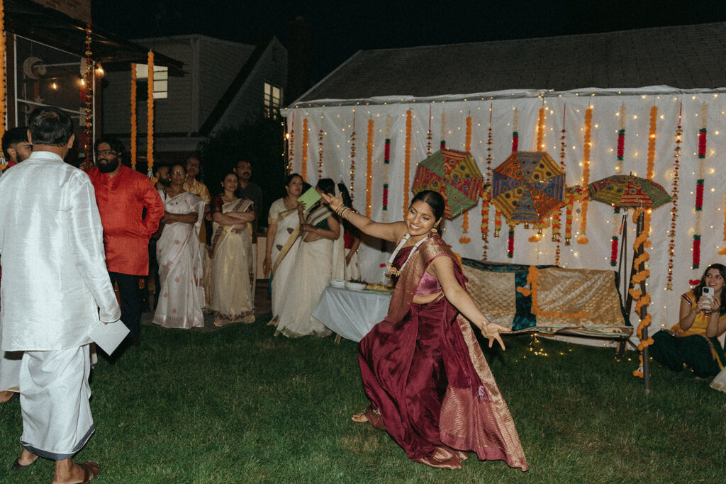 Guest performing a joyful dance while family watches during Catholic Indian wedding celebration — Elsie Goodman Photography.