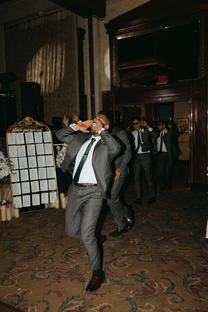 Groomsmen make an energetic entrance at a Crest Hollow Country Club wedding, celebrating a lively Catholic Indian wedding with choreographed moves, captured by Elsie Goodman Photography for an unforgettable Indian wedding photo gallery.