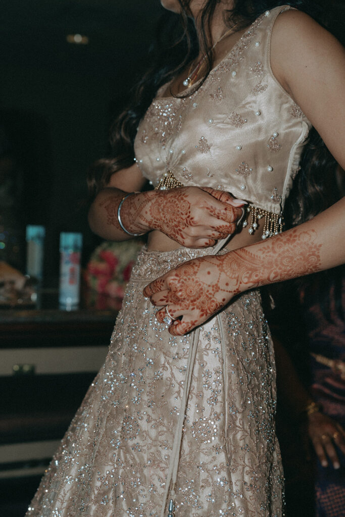 Close-up of the bride’s intricate mehndi and sparkling lehenga during an Indian Catholic wedding celebration at Crest Hollow Country Club, photographed by Elsie Goodman Photography.
