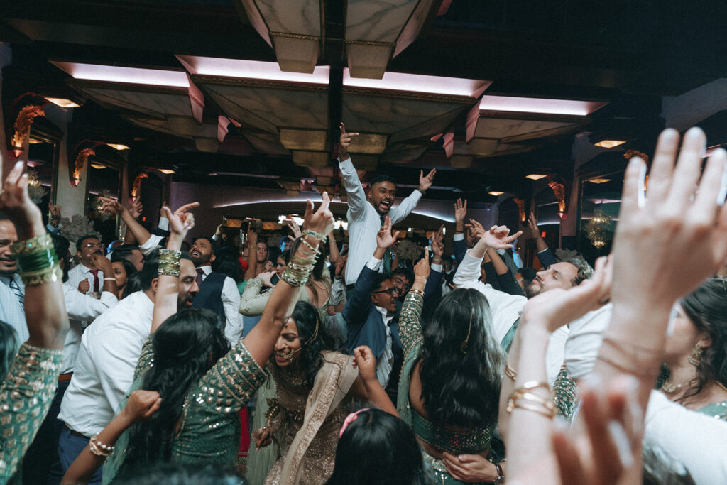 Groom lifted in the air surrounded by dancing friends and family during an electric Catholic Indian wedding reception at Crest Hollow Country Club, a top Indian wedding venue on Long Island, documented by Elsie Goodman Photography.