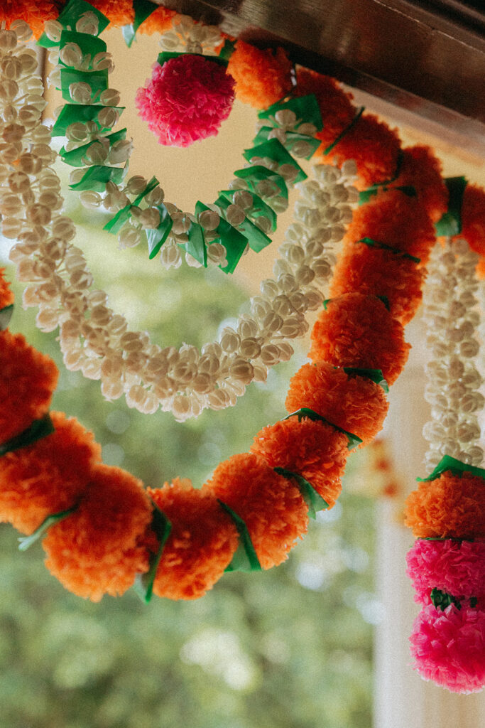 Close-up of vibrant marigold and jasmine wedding garlands hanging before Catholic Indian wedding — Elsie Goodman Photography.