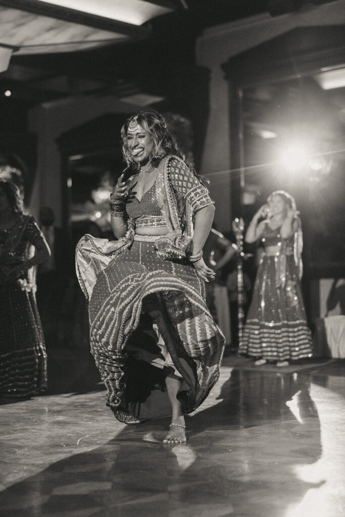 A joyful Indian wedding dance performance captured mid-spin during the reception at Crest Hollow Country Club, part of an Indian Catholic wedding celebration by Elsie Goodman Photography.