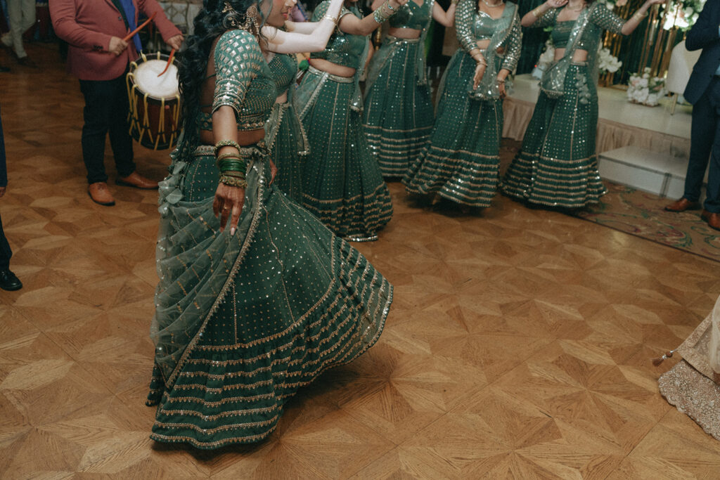 Bridesmaids dressed in matching green lehengas dancing during a Catholic Indian wedding at Crest Hollow Country Club, one of Long Island’s best Indian wedding venues, captured in the Indian wedding photo gallery by Elsie Goodman Photography.