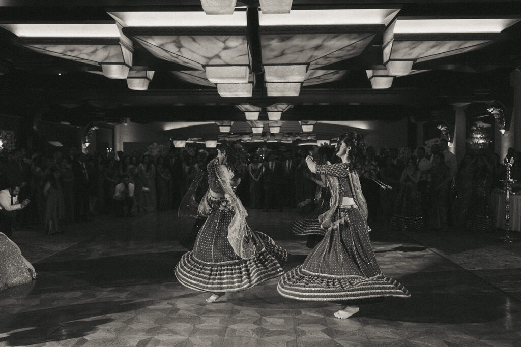 Black-and-white capture of synchronized bridesmaids twirling in traditional green Indian catholic wedding dresses during a Crest Hollow Country Club wedding celebration, beautifully photographed by Elsie Goodman Photography for the Indian wedding photo gallery.