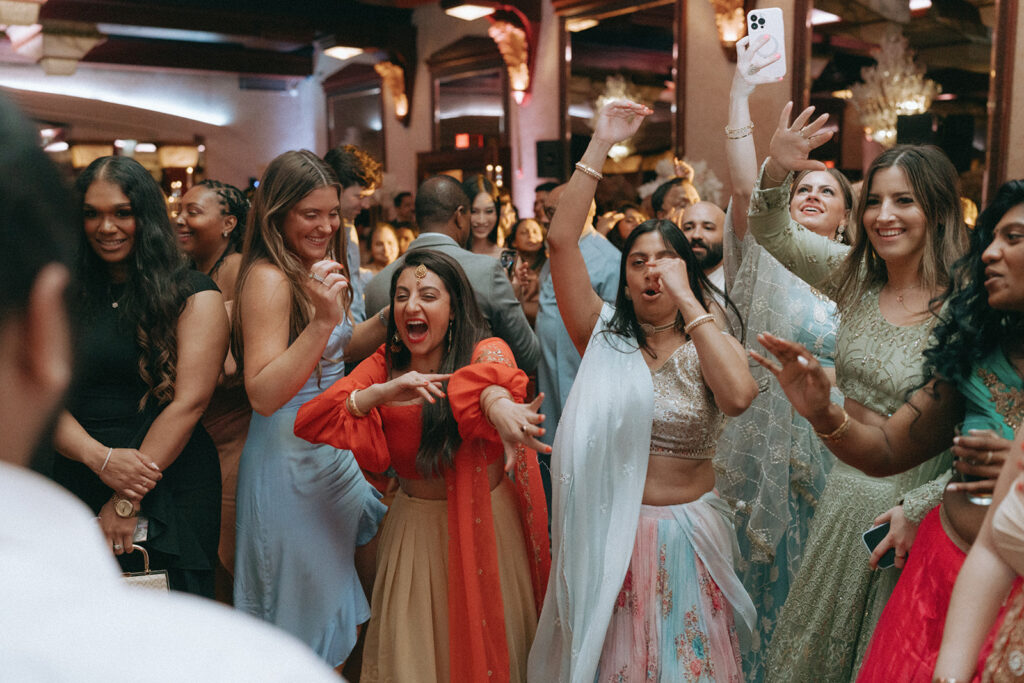 A lively dance floor filled with colorful lehengas and infectious energy at a Crest Hollow Country Club wedding, showcasing vibrant Catholic Indian wedding moments by Elsie Goodman Photography for the Indian wedding photo gallery.
