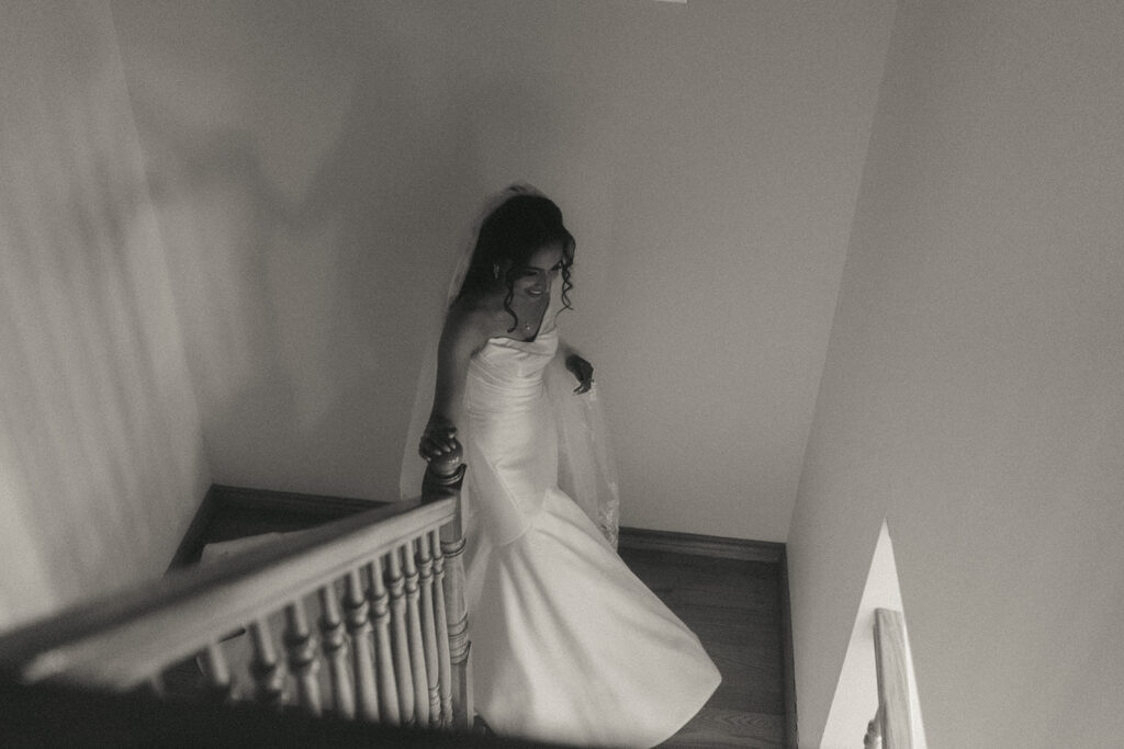 Bride walking down the staircase holding her dress during her Catholic Indian wedding day preparations, captured by Elsie Goodman Photography.