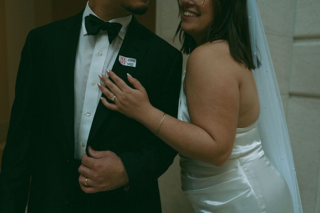 Close-up of wedding rings and MET ticket on a suit jacket after at a NYPL wedding, by Elsie Goodman.