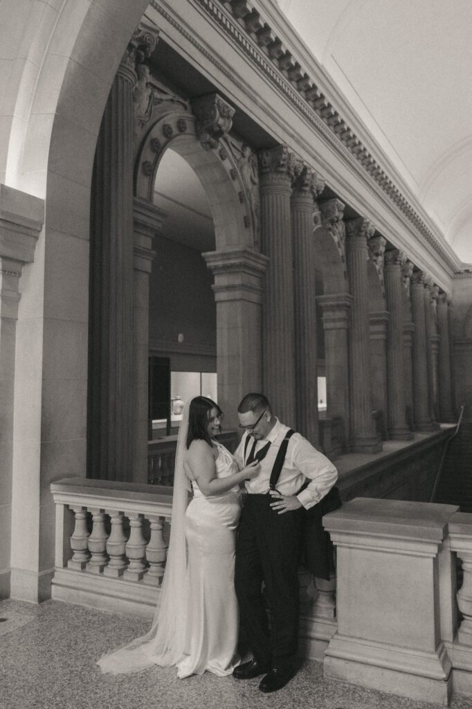 Bride adjusts groom's tie inside The Met during their NYPL elopement photos by Elsie Goodman.