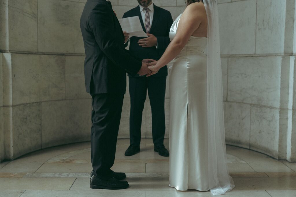 Bottom half of the bride and groom standing at the altar during their NYPL wedding, by Elsie Goodman.