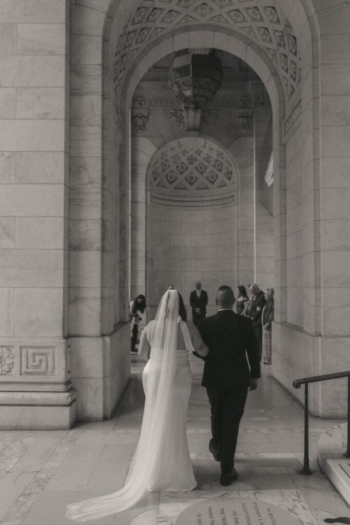 Bride and father walk down the aisle at NYPL elopement, shot by Elsie Goodman.
