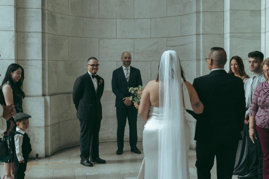 Bride walks down the aisle inside the New York Public Library for her NYPL wedding ceremony, by Elsie Goodman.