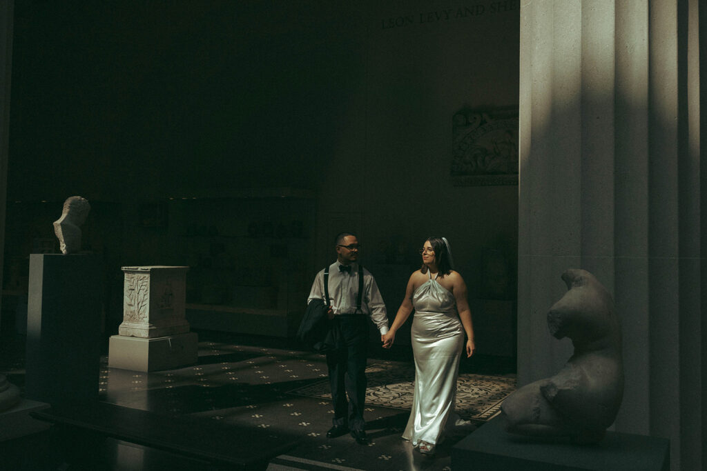Bride and groom lit up on dark background at the MET after their NYPL elopement, captured by Elsie Goodman.