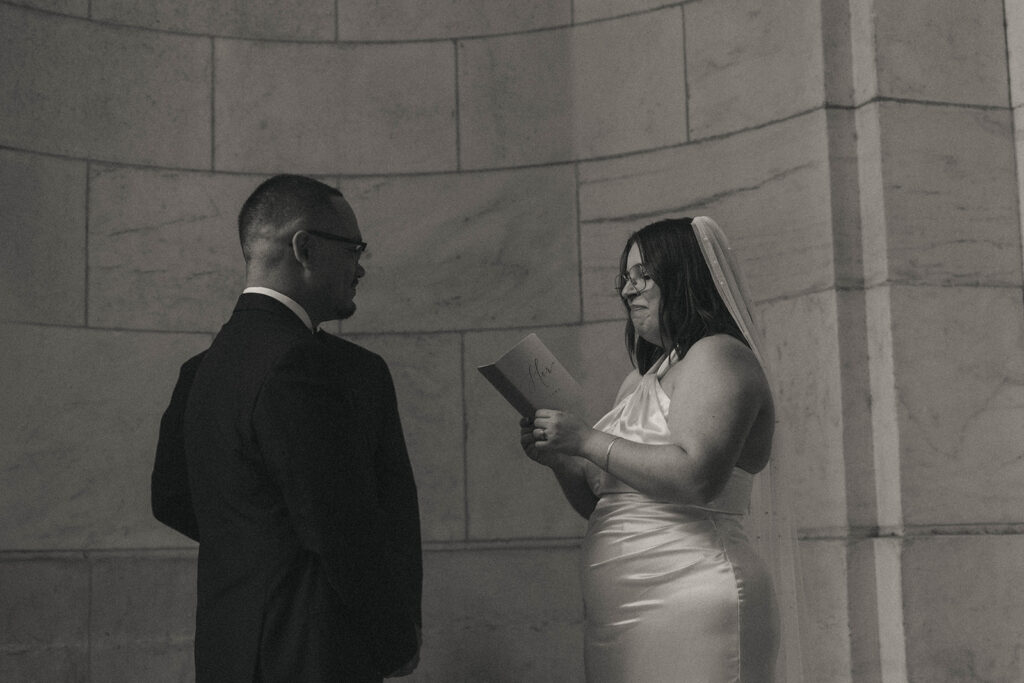 Black and white photo of bride reading vows during New York Public Library elopement, by Elsie Goodman.
