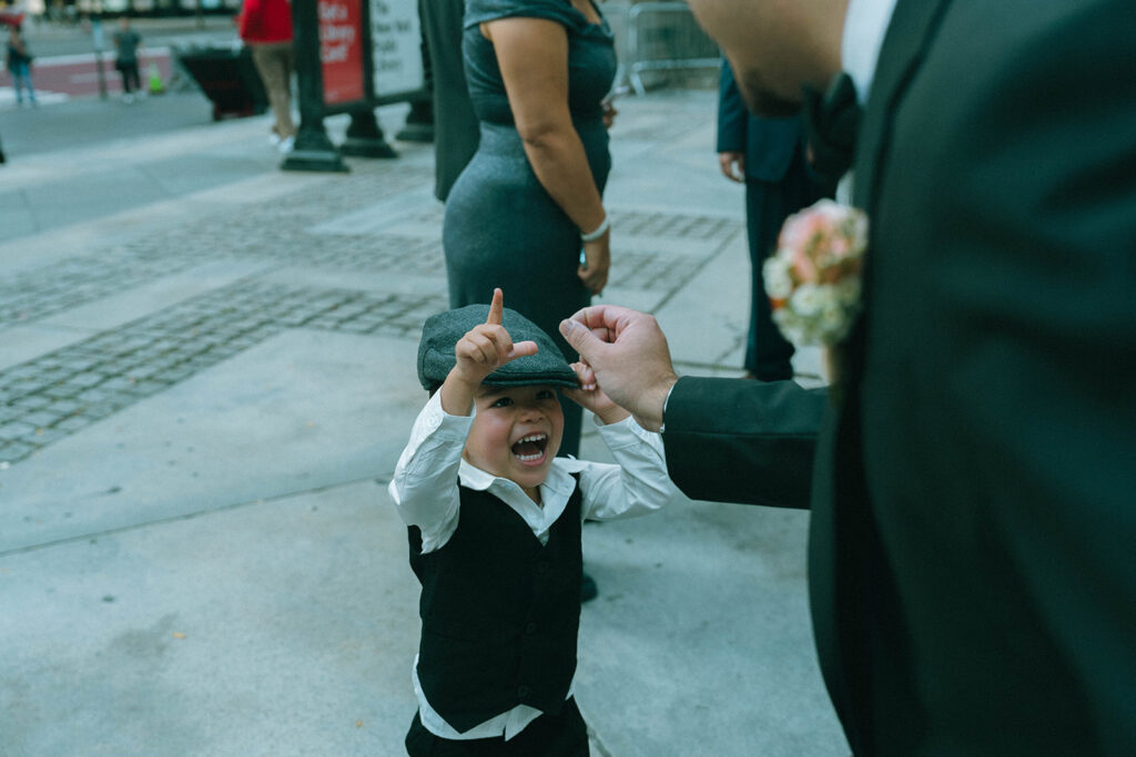 Little ring bearer laughing outside of New York Public Library after elopement, shot by Elsie Goodman.