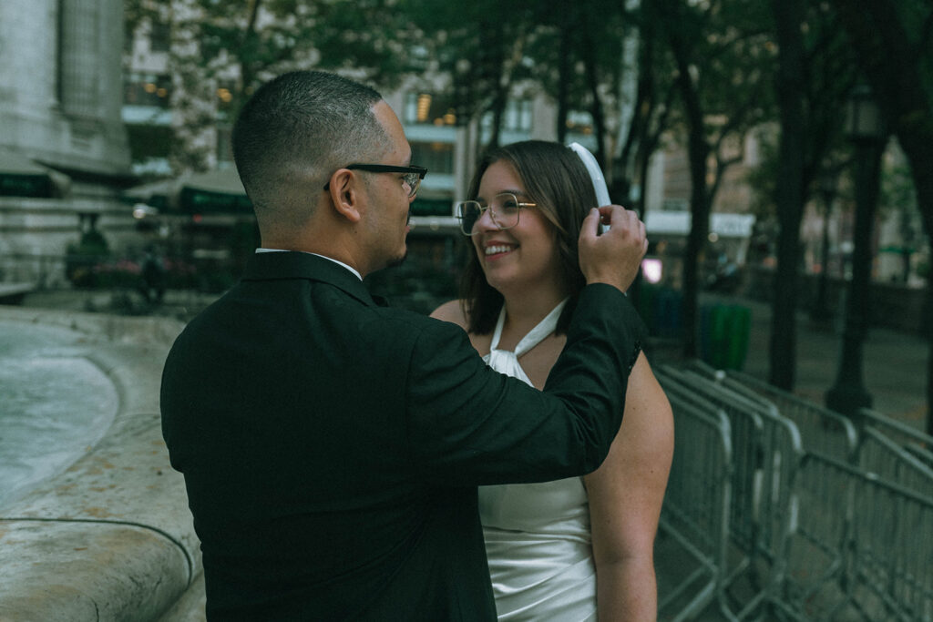Portrait of groom fixing bride's veil after NYPL wedding, captured by Elsie Goodman Photography.