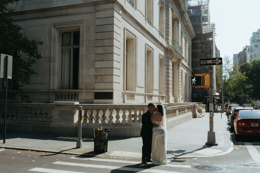 Bride and groom kiss at a crosswalk in NYC after their New York City elopement, shot by Elsie Goodman.