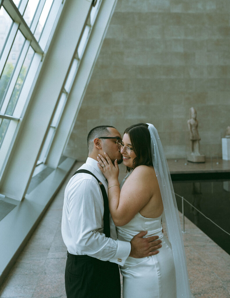 Close up of groom kissing bride's cheek at the MET after eloping in NYC, shot by Elsie Goodman Photography.
